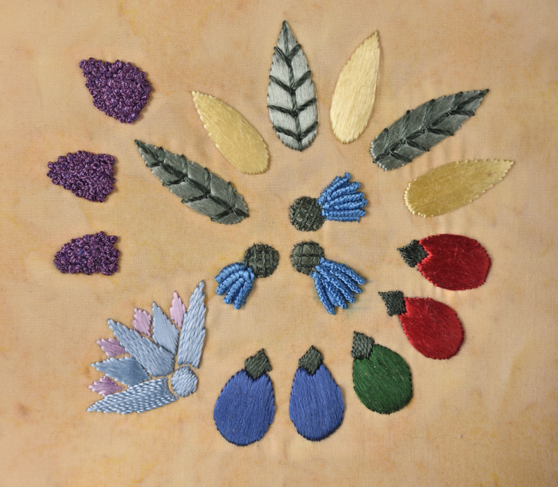 Photograph of an embroidery depicting faience beads from a necklace. The embroidery uses glossy flat silk thread, and the stitches are chosen to help bring to mind not just the beads, but the fruits and flowers that inspired them.